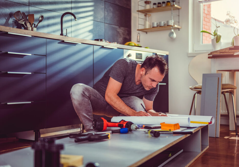 Man working on a new kitchen installation and looking at blueprints