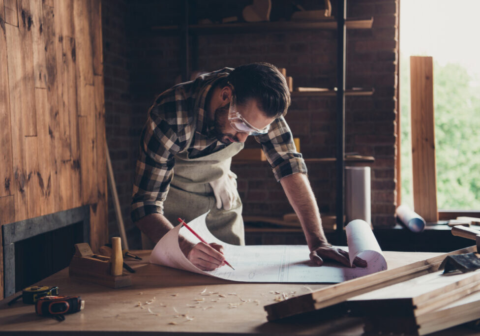 Draft workbench creative profession restoration people person industry concept. Close up photo portrait of smart handsome concentrated workman architect making notes analyzing architecture design plan