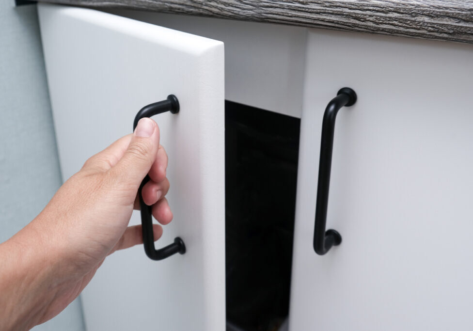 Female hand open white kitchen cabinet,cupboard doors, close up.